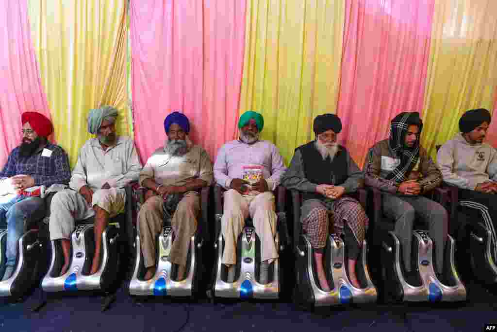 Farmers get foot massage inside a tent as they continue to demonstrate against the central government's recent agricultural reforms, blocking a highway at the Delhi-Haryana state border in Singhu, India.