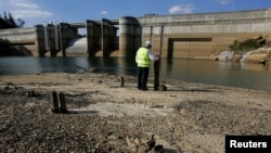 Petugas pengelola air minum Australia (Sydney Catchment Authority), Dick Pearson, menunjukkan tinggi air yang mencapai level terendah di bendungan Warragamba Sydney. (Foto: dok).