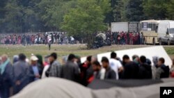 FILE - Migrants and refugees line up for food distribution at the northern Greek border point of Idomeni, Greece, May 2, 2016.