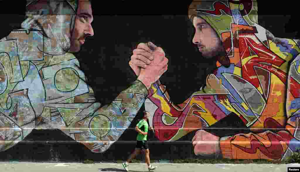 A jogger runs past a mural on a wall in Vienna, Austria.