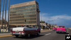 FILE - Tourists ride classic convertible cars on the Malecon in Havana, Cuba, Oct. 3, 2017. 