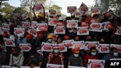 Protesters hold up signs supporting the Civil Disobedience Movement (CDM) at a demonstration against the military coup in Yangon on February 14, 2021. (Photo by YE AUNG THU / AFP)