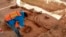 In this undated photo released May 21, 2020, by Mexico's National Institute of Anthropology and History (INAH), an archaeologist works at the site where bones of about 60 mammoths were discovered near Mexico City.