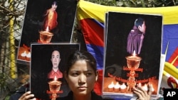A Tibetan exile holds the photographs of Tibetan monks who have self immolated in Tibet protesting Chinese government, during a demonstration to support three fellow Tibetan exile students Tselo Gyal, 21, Lugoen Thar, 21, and Gyaltsen, 19 in Bangalore, In