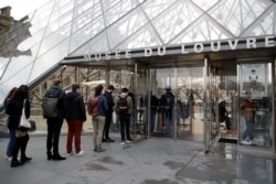 Pengunjung memasuki Piramida Louvre di Paris saat museum Louvre dibuka kembali untuk umum, setelah lebih dari enam bulan ditutup karena pandemi COVID-19 di Perancis, 19 Mei 2021.