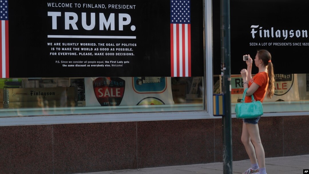 Seorang wanita memotret poster penyambutan Presiden AS, Donald Trump, dan Presiden Rusia, Vladimir Putin, di sebuah toko di pusat kota Helsinki, 14 Juli 2018 (foto: AP Photo/Markus Schreiber)