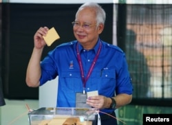 Malaysia's Prime Minister Najib Razak of Barisan Nasional (National Front) looks at his ballot before casting it, at a polling station during Malaysia's general election in Pekan, Pahang, Malaysia, May 9, 2018.