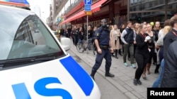 Personas se alejan de la tienda por departamentos Ahlens, en el centro de Estocolmo, luego que un camión arrolló a varias personas y se estrelló contra el escaparate de la tienda.