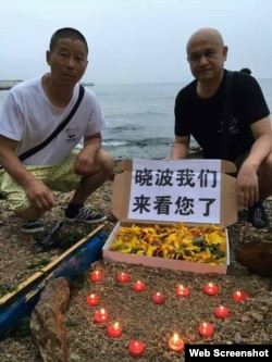 姜建军（左）、王承刚在大连老虎滩海边祭奠两天前葬于附近海域的刘晓波。（2017年7月17日 推特图片）