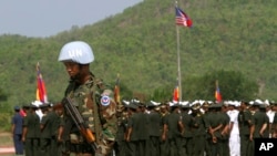 A Cambodian army soldier, foreground, wears a U.N. helmet while standing guard during a U.S.-backed peacekeeping exercise dubbed "Angkor Sentinel 2014" at the Cambodian tank command headquarters in Kampong Speu province, 60 kilometers (37 miles) west of Phnom Penh, Cambodia, Monday, April 21, 2014. The U.S. and Cambodia on Monday commenced Angkor Sentinel, an annual military exercise designed to promote regional peace and security. (AP Photo/Heng Sinith)