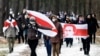 FILE - Opposition supporters carrying former white-red-white flags of Belarus parade through the streets during a rally against the Belarus presidential election results in Minsk, on Dec. 13, 2020.