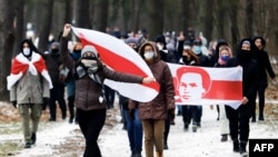 FILE - Opposition supporters carrying former white-red-white flags of Belarus parade through the streets during a rally against the Belarus presidential election results in Minsk, on Dec. 13, 2020.