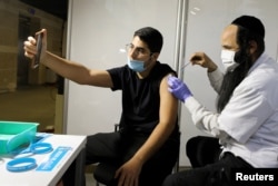 A man receives a vaccination against the coronavirus disease (COVID-19) at a temporary Clalit healthcare maintenance organisation (HMO) vaccination centre, at a sports arena in Jerusalem February 25, 2021. Picture taken February 25, 2021. REUTERS/Ammar Awad