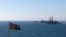 FILE - An Azerbaijan state flag flutters in the wind on an oil platform in the Caspian Sea east of Baku, Jan. 22, 2013. 