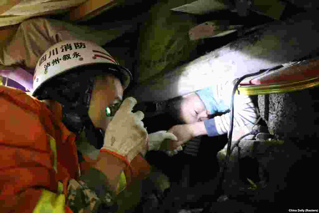 A firefighter helps a boy stranded in debris following a landslide in Xuyong county, Sichuan province, China, Dec. 9, 2018.