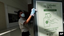 Un trabajador limpia un letrero que explica las medidas de higiene para frenar la propagación de COVID-19 en Multiplaza Mall, donde las tiendas ya están listas para abrir, en Ciudad de Panamá, el lunes 17 de agosto de 2020.