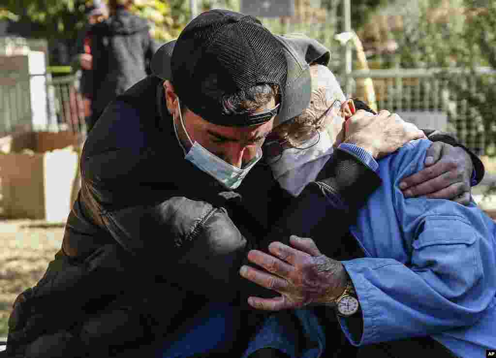 Local residents comfort each other as they watch members of rescue services working on the search for survivors in the debris of a collapsed building, in Izmir, Turkey, Monday, Nov. 2, 2020. Rescue teams continue ploughing through concrete blocs and debri