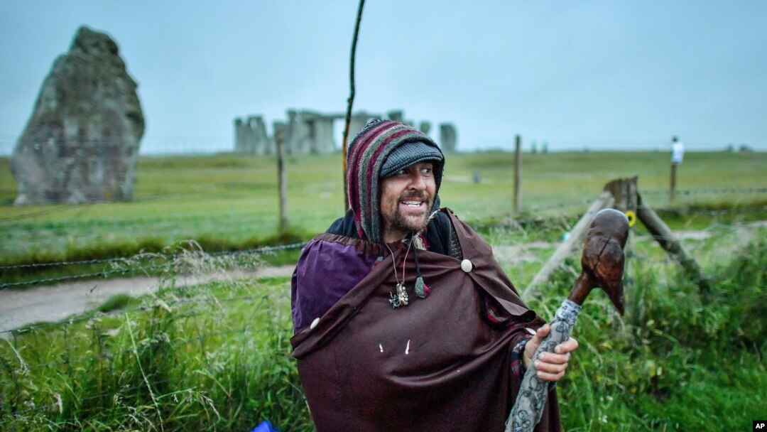 Un hombre posa delante del cerrado monumento de Stonehenge mientras personas se reúnen para celebrar el amanecer del día más largo en el hemisferio norte, el solsticio de verano, cerca de Salisbury, Inglaterra, el domingo 21 de junio de 2020.
