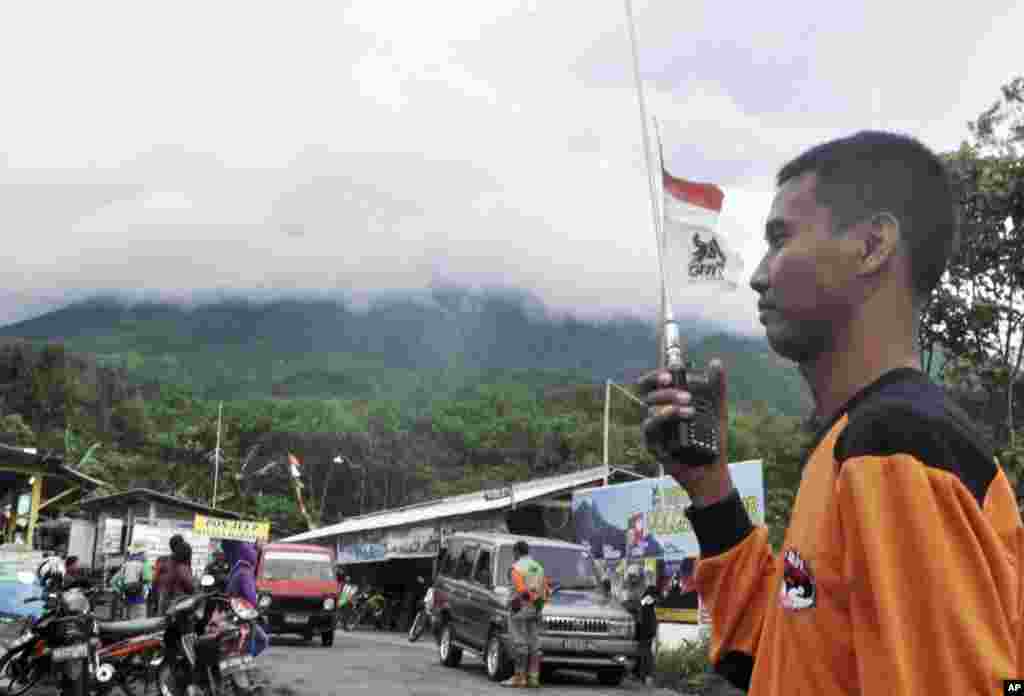 Seorang petugas penyelamat di Cangkringan, dekat Yogyakarta (18/11), dengan latar belakang Gunung Merapi. (AP/Slamet Riyadi)