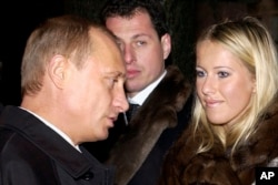 FILE - Russian President Vladimir Putin, left, speaks to Ksenia Sobchak, daughter of former St. Petersburg mayor Anatoly Sobchak at a cemetery in St. Petersburg, Russia, Nov. 29, 2003.