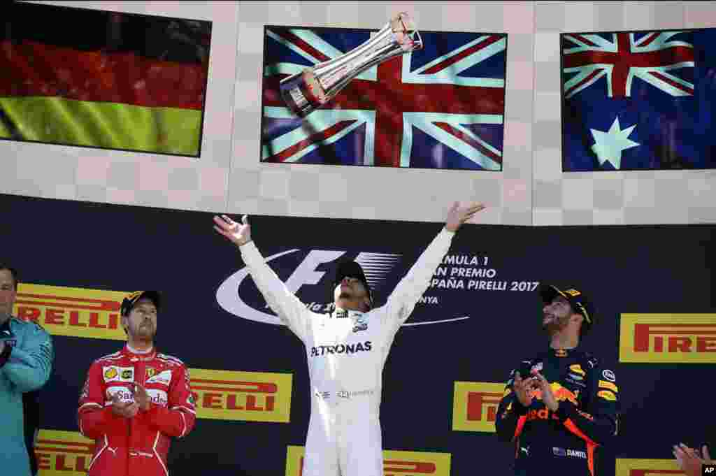 Mercedes driver Lewis Hamilton of Britain, center, throws his trophy in the air after winning the Spanish Formula One Grand Prix at the Barcelona Catalunya racetrack in Montmelo, Spain.