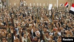 File - Shi'ite Muslim rebels hold up their weapons during a rally against air strikes in Sanaa, Yemen, March 2015.