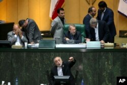 FILE - Head of Iran's Atomic Energy Organization Ali Akbar Salehi, bottom, speaks in an open session of parliament while discussing a bill on Iran's nuclear deal with world powers, in Tehran, Iran, Oct. 11, 2015.