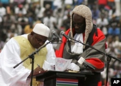 FILE - Gambia President Adama Barrow, left, signs a document during his inauguration ceremony in Banjul, Feb. 18, 2017.