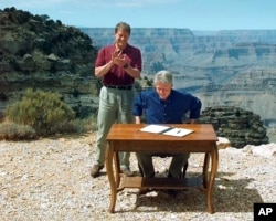 FILE - In this Sept. 18, 1996, photo, vice president Al Gore applauds after president Bill Clinton signs a bill designating about 1.7 million acres of land in southern Utah's red-rock cliff as the Grand Staircase-Escalante National Monument.