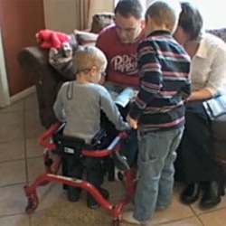 A family of four spends time together reading a book. The study aims to find the effects of genetic and environmental influences.