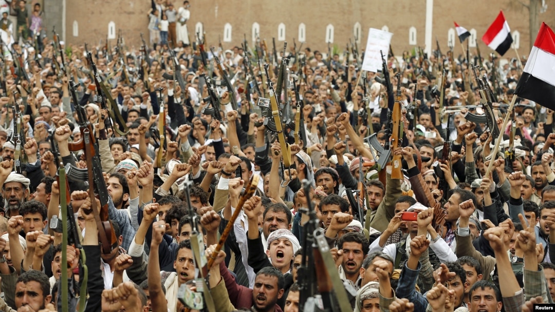 File - Shi'ite Muslim rebels hold up their weapons during a rally against air strikes in Sanaa, Yemen, March 2015.