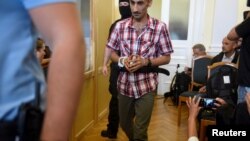 Four men, charged with the killing of 71 migrants at the height of Europe's migrant crisis in 2015, are escorted by police into a court in Kecskemet, Hungary, June 14, 2018.