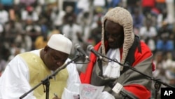 In this photo taken Feb. 18, 2017, Gambia President Adama Barrow, left, signs a document during his inauguration ceremony in Banjul, Gambia. 