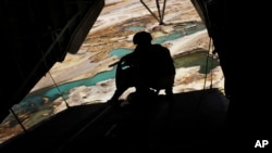 FILE - A U.S. Marine helicopter door gunner holds a heavy machine gun during a flight over Nimroz province on the border with the volatile Helmand province in southern Afghanistan.