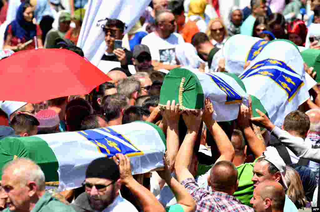 Bosnian Muslims carry caskets of the 33 newly identified bodies of the 1995 Srebrenica massacre before their inhumation at the Potocari Memorial Cemetery near the Eastern-Bosnian town of Srebrenica.