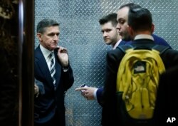 FILE - Retired Lt. Gen Michael Flynn, left, his son Michael G. Flynn, second from left, and Boris Epshteyn, a spokesman for President-elect Donald Trump, third from left, board an elevator at Trump Tower in New York.