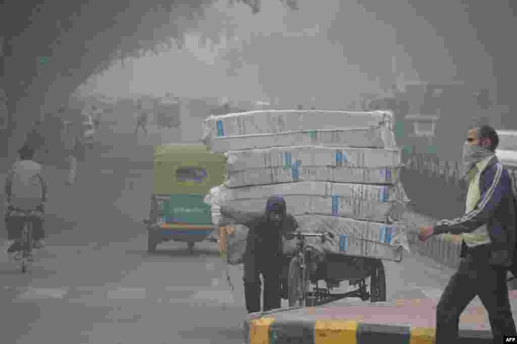 A man (R) with his face covered walks amid heavy smog along a street in New Delhi, India.