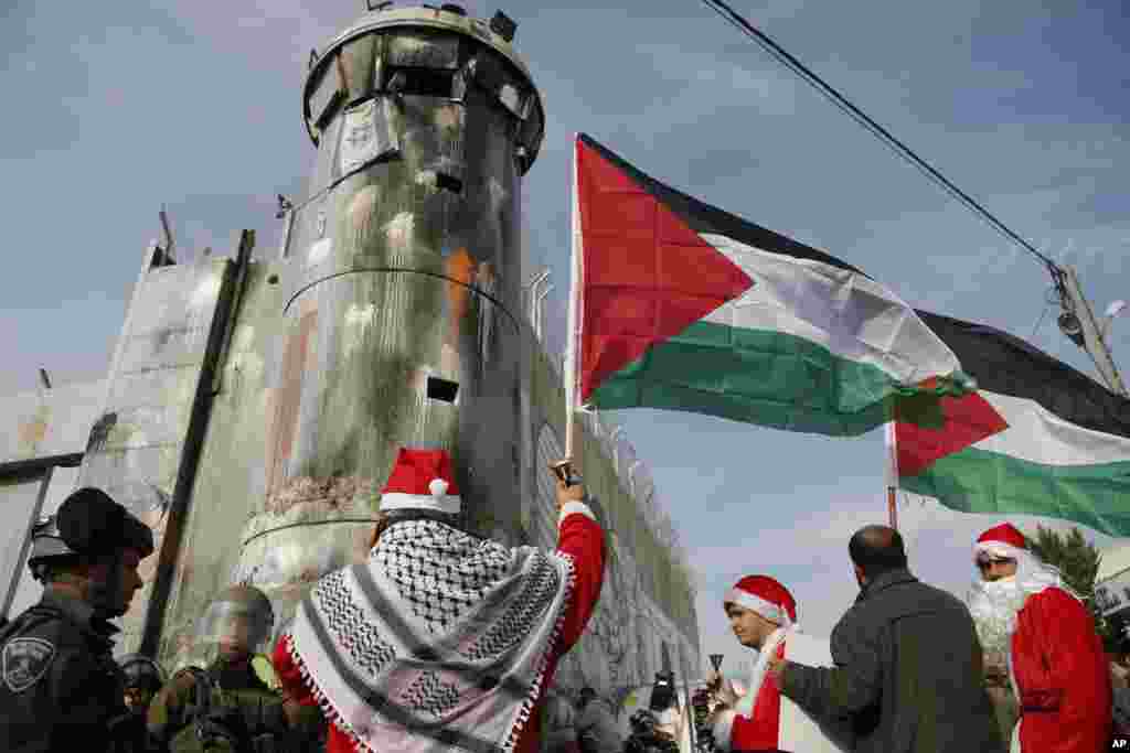 2017年12月23日，在约旦河西岸城市伯利恒，巴勒斯坦人身穿圣诞老人衣服举行抗议活动，与以色列边防警察对峙。