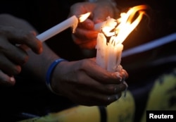 FILE - Filipino photojournalists light candles to commemorate the first anniversary of the killings in Maguindanao in southern Philippines during a protest rally in Manila, Nov. 23, 2010.