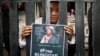 FILE - An exile Tibetan poses as Runggye Adak as he stands behind bars depicting jail during a street performance by Tibetan activists in Dharmsala, India, Aug.1, 2014. 