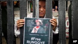 FILE - An exile Tibetan poses as Runggye Adak as he stands behind bars depicting jail during a street performance by Tibetan activists in Dharmsala, India, Aug.1, 2014. 