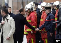 FILE - French President Emmanuel Macron (L) shakes hands with a firefighter during a visit in the streets of Paris on Dec. 2, 2018, a day after clashes during a protest of Yellow vests.