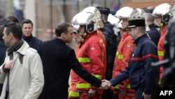 French President Emmanuel Macron shakes hands with a firefighter during a visit in the streets of Paris on Dec. 2, 2018, a day after clashes during a protest of 'yellow vests' against rising oil prices and living costs.