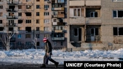 Arhiva - Dečak prolazi pored zgrade oštećena tokom konflikta u oblasti Donjecka, u Ukrajini, 25. novembra 2017.