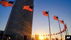 Tourists walk around the base of the Washington Monument on Presidents Day weekend as the sunsets Sunday, Feb. 19, 2017, in Washington. (AP Photo/J. David Ake)