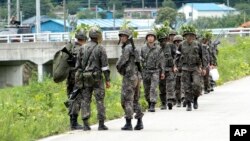 South Korean army soldiers patrol to search for a South Korean conscript soldier who is on the run after a shooting incident in Goseong, South Korea, Sunday, June 22, 2014.