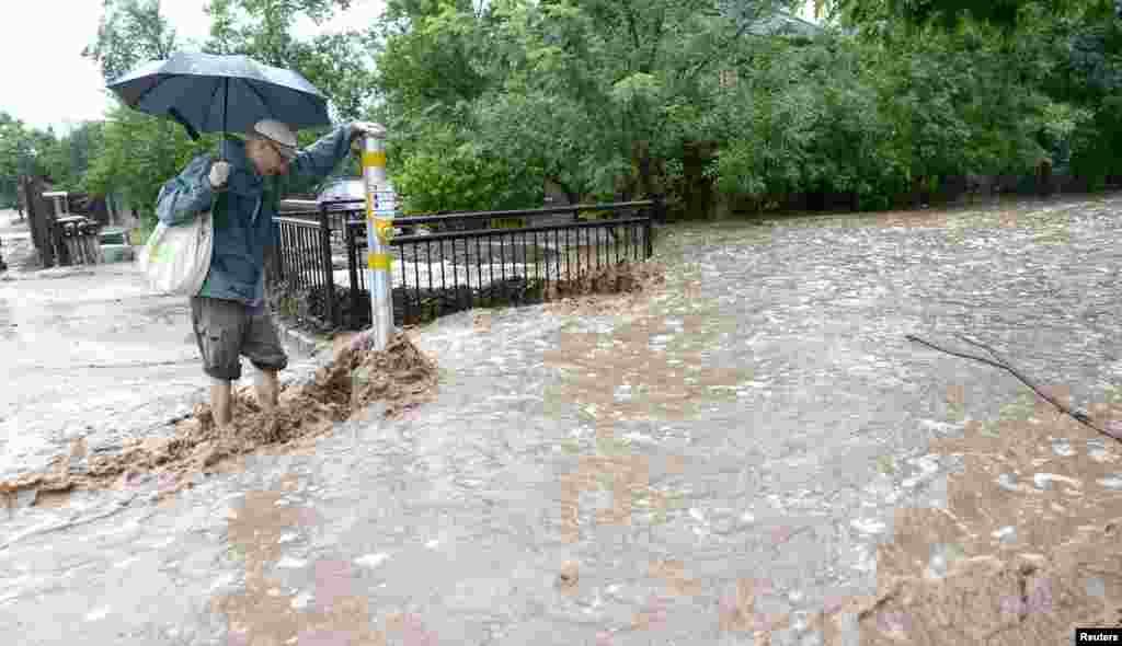 Matthew Messner looks for a way to cross the sidewalk covered by heavy rains in Boulder, Colorado, Sept. 12, 2013.