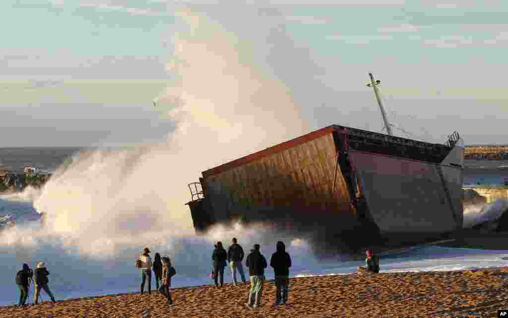 People look the Spanish cargo ship "Luno" that slammed into a jetty in the choppy Atlantic Ocean waters and broke in two, off Anglet, southwestern France. The ship had been heading to a nearby port when its engine failed and the rough waves carried it into the jetty.