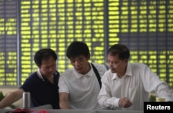 Investors talk in front of an electronic board showing stock information, filled with green figures indicating falling prices, at a brokerage house in Nantong, Jiangsu province, China, July 3, 2015.