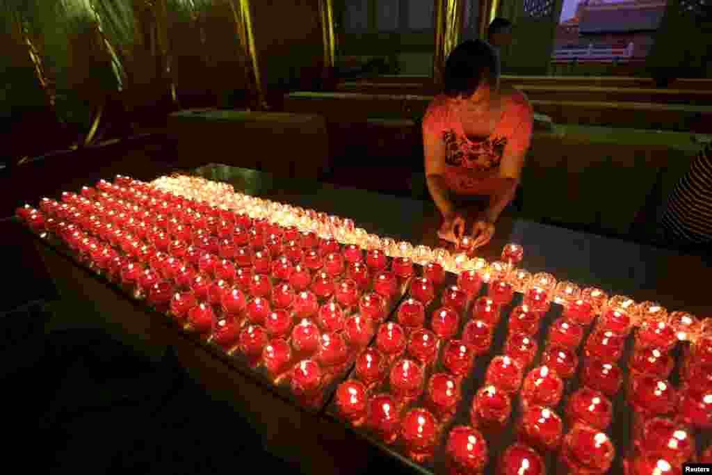 Seorang perempuan meletakkan lilin-lilin sebelum acara doa bersama bagi korban yang tewas dalam ledakan Kamis di distrik Binhai, di kuil&nbsp;​Chaoyin, Tianjin, China. Ledakan dahsyat tersebut menewaskan 56 orang.
